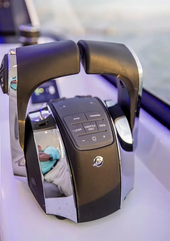 Boat throttle control with buttons for sync, transfer, one lever, throttle only, and dock; reflects a hand holding a blue item.